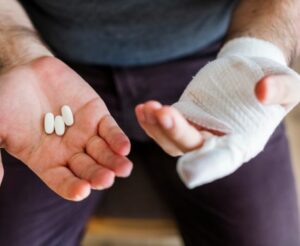 man with hand injury taking pills
